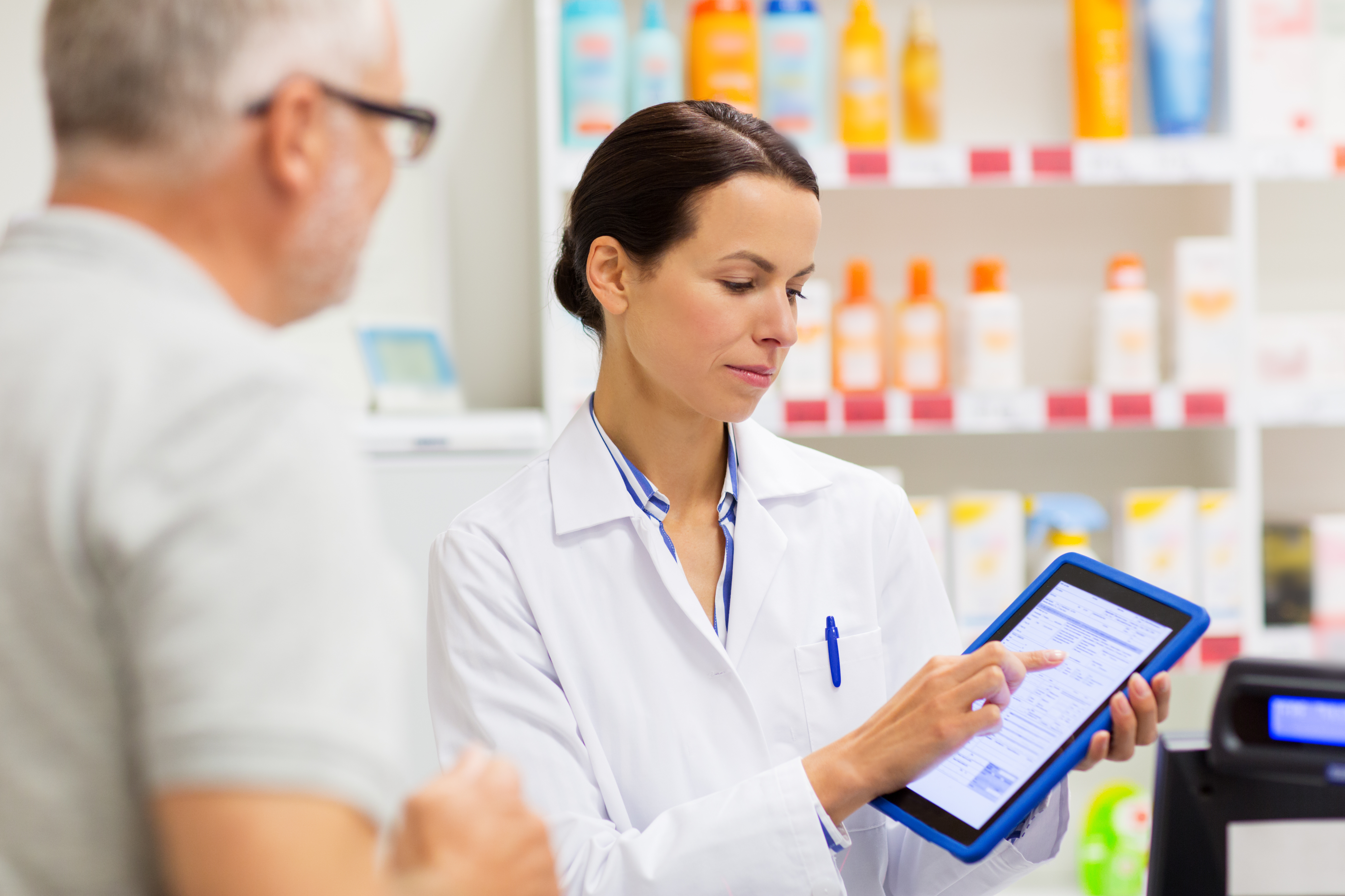 Female pharmacist showing tablet to patient 