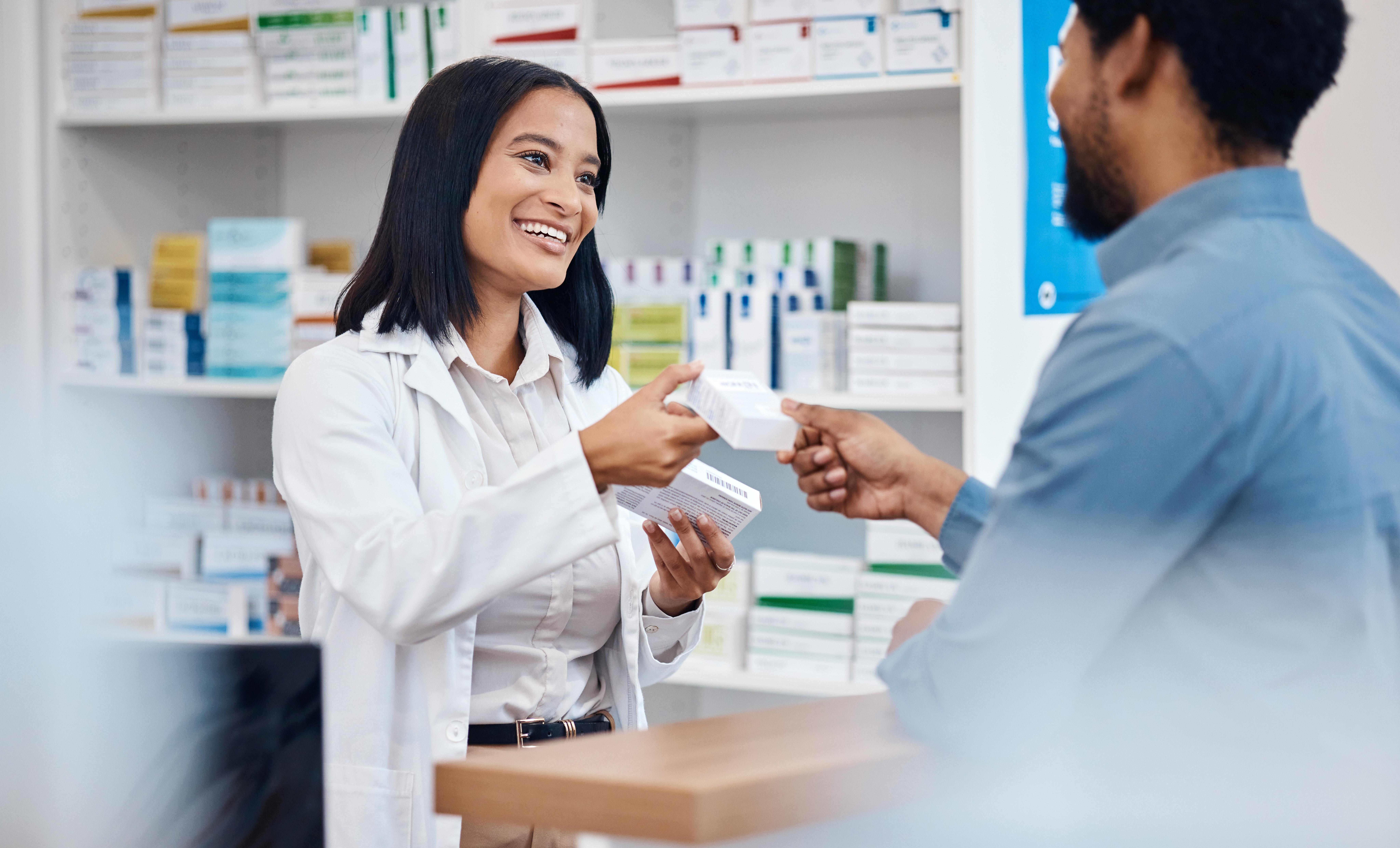Happy pharmacist handing a prescription to customer