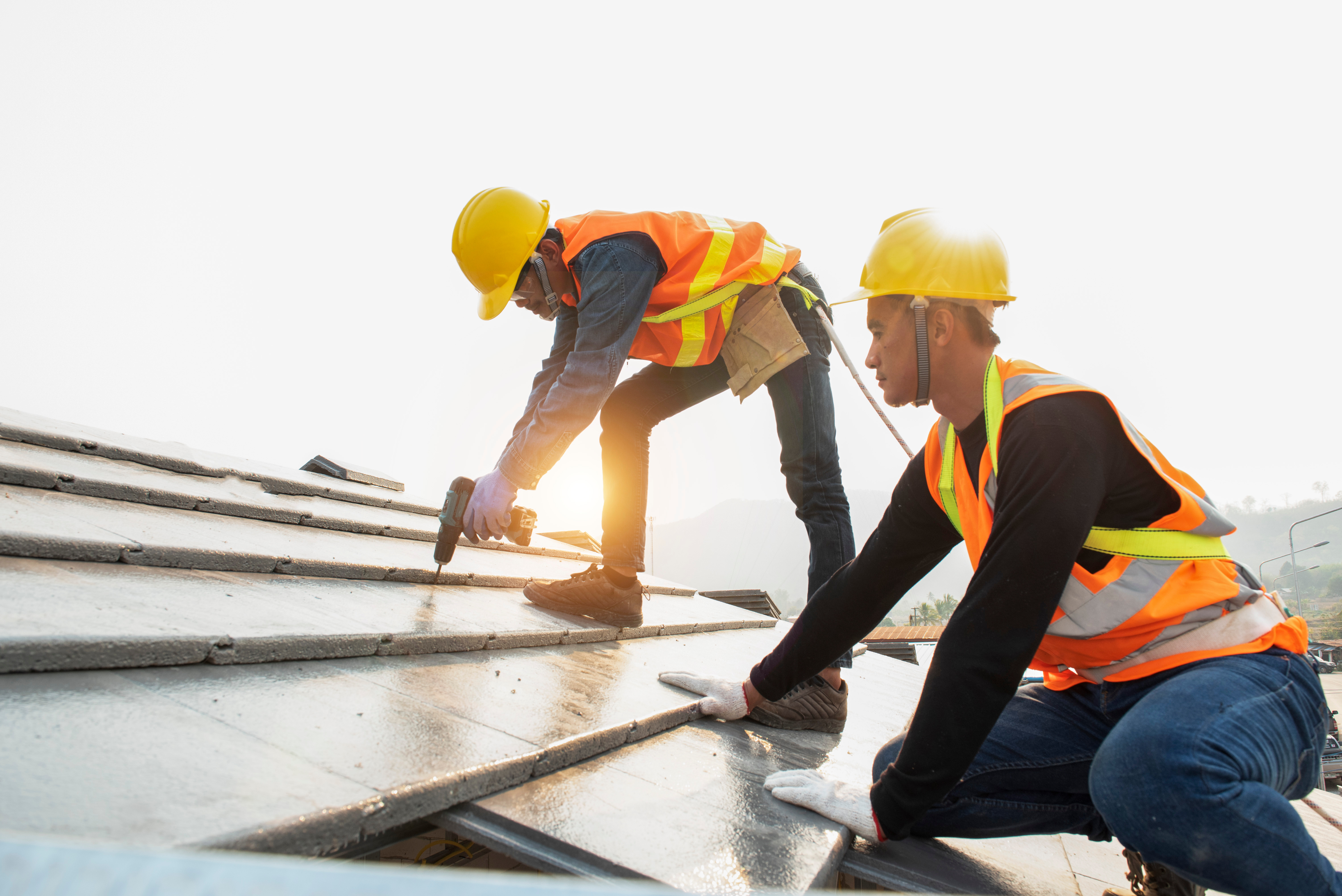 roof-construction workers stand on tiled roof 