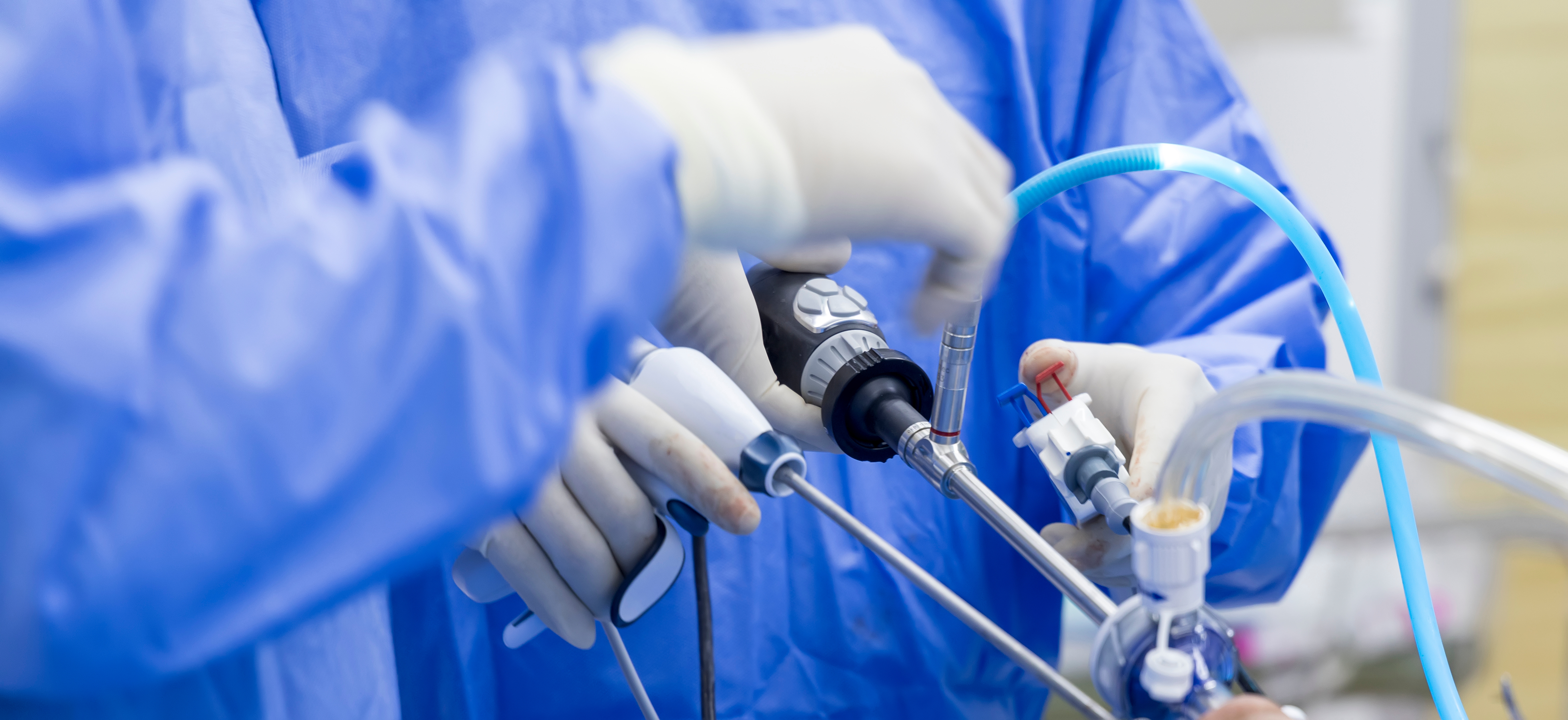 Doctor in blue sterile surgical gown suite doing minimal invasive surgery with camera and instrument