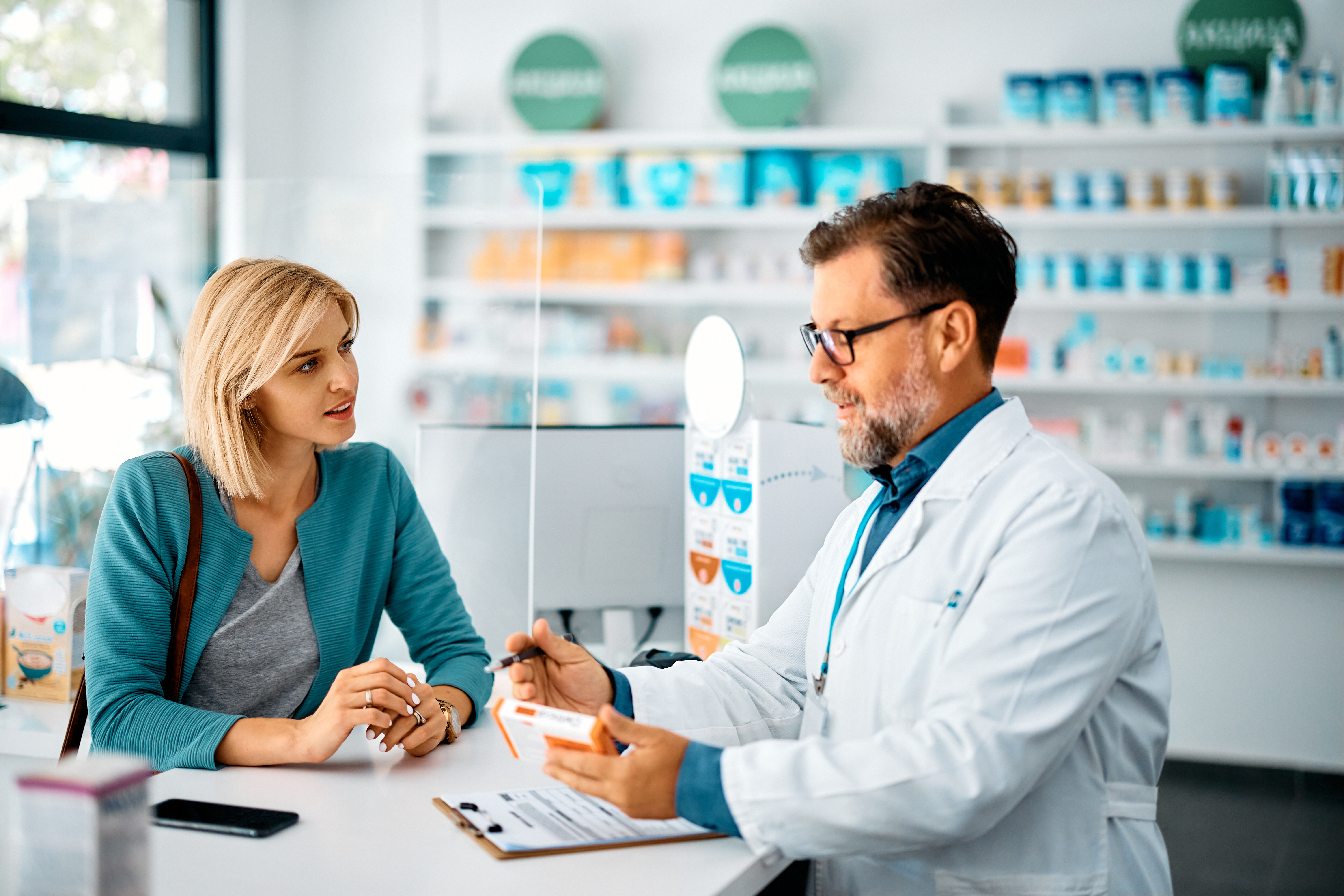Male pharmacist discussing medication with female customer in pharmacy