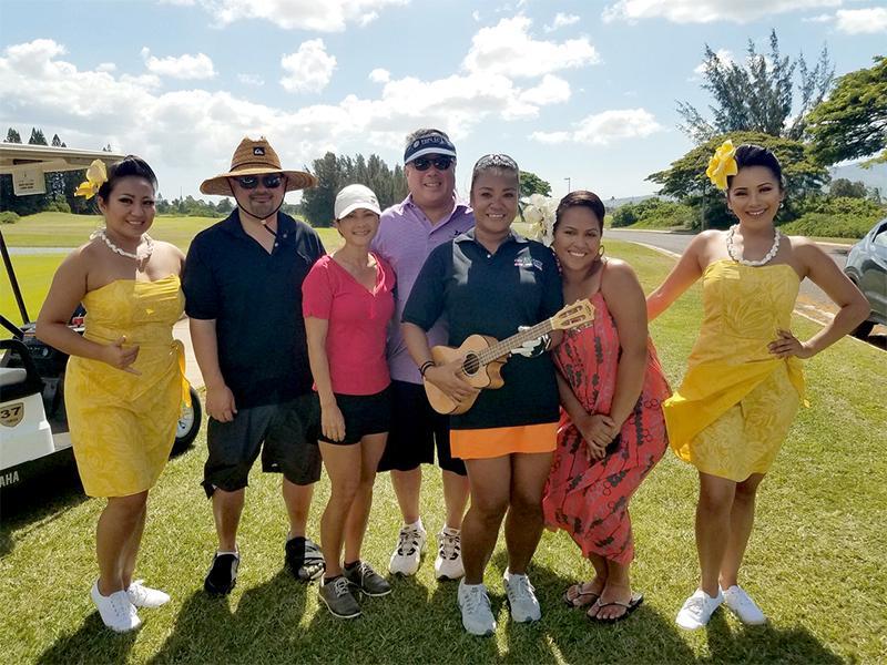 People smiling while holding a ukulele on a golf course