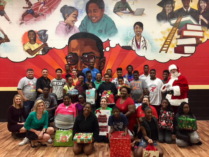 Group of people standing with Santa in front of large painted wall mural