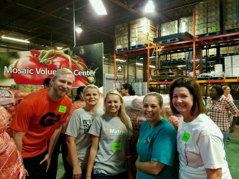Group of five people smiling inside a warehouse