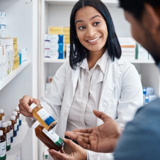Pharmacist looking at prescriptions with customer