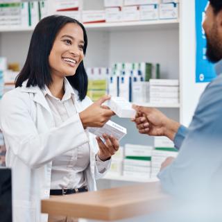 Happy pharmacist handing a prescription to customer