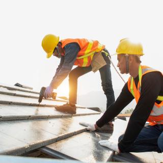 roof-construction workers stand on tiled roof 