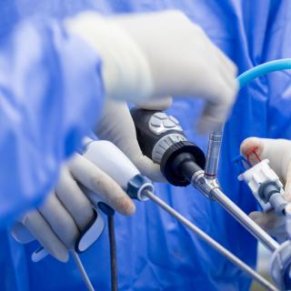Doctor in blue sterile surgical gown suite doing minimal invasive surgery with camera and instrument