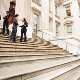 People in corporate suits on steps of legislative building