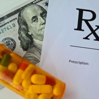 prescription bottle tipped over on top of Rx pad and hundred dollar bill
