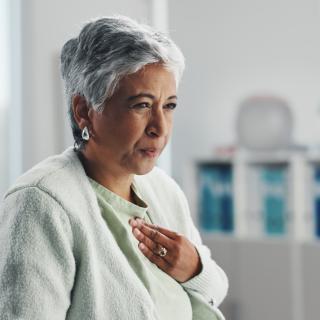 Senior, sick woman and chest pain with infection at hospital for clinic checkup, visit or exam