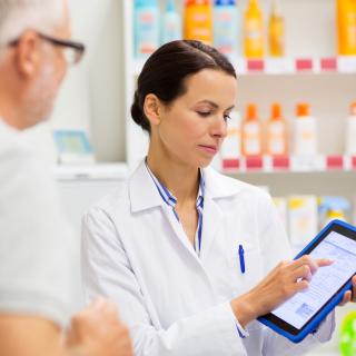 Pharmacist holding tablet while helping patient