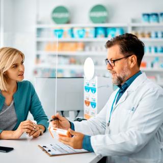 Male pharmacist discussing medication with female customer in pharmacy